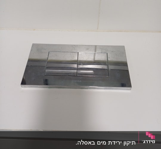 לחצן הדחה כסוף על קיר לבן
